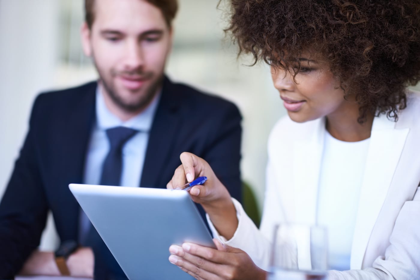 Une femme et un homme consultent une tablette, la femme montrant l'écran avec un stylo
